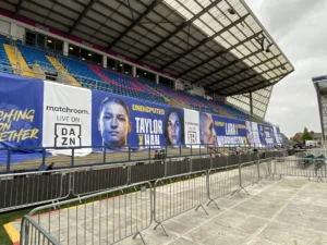 Boxing event graphics displayed at the stadium. It features fighters. The theme is matching stadium colours- it is blue, white and yellow