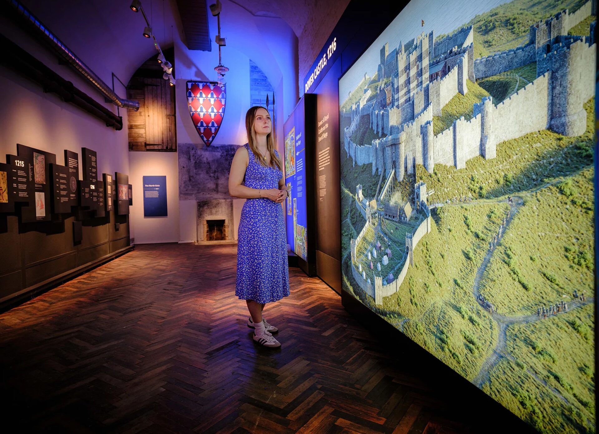 Eco durable museum graphics and signage at Dover Castle- the lightbox features the drone picture of the castle. Woman in blue dress is looking at the graphic.