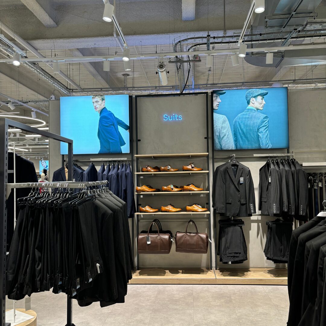 Lightboxes featuring Marks and Spencer menswear, they are placed over the shopping display. On the display, there are suits, duffle bags and shoes.