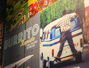 Closeup of barburrito's colourful wall vinyl. It says 'Burrito Rapido, Lunch time rush? No problemo!' Next to it there is a picture of a man holding the back of the car.